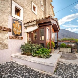 Ingresso esterno hotel Opi La Pieja con insegna del ristorante, terrazza panoramica e vista sulle montagne di Opi