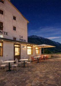 Terrazza panoramica hotel Opi La Pieja di sera con ristorante illuminato, tavoli esterni e vista sulle montagne