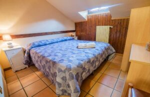 Camera mansardata matrimoniale della Dimora Fresilia con luce calda e rivestimenti in legno a Opi
