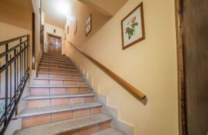 Scala interna della Dimora Fresilia in palazzo storico a Opi con corrimano, pareti chiare e dettagli sobri