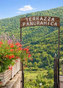 Ingresso terrazza panoramica ristorante Opi con fioriere, vista sul verde e scorcio naturale sulle montagne