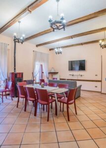 Sala comune dimora storica Opi con camino, tavolo conviviale, travi a vista e ambiente accogliente