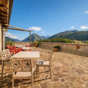 Terrazza panoramica ristorante Opi con tavoli all’aperto, pavimento in pietra e vista sulle montagne
