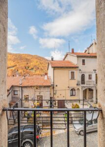 Vista sul borgo da dimora storica Opi con balcone in ferro, case in pietra e paesaggio d’autunno