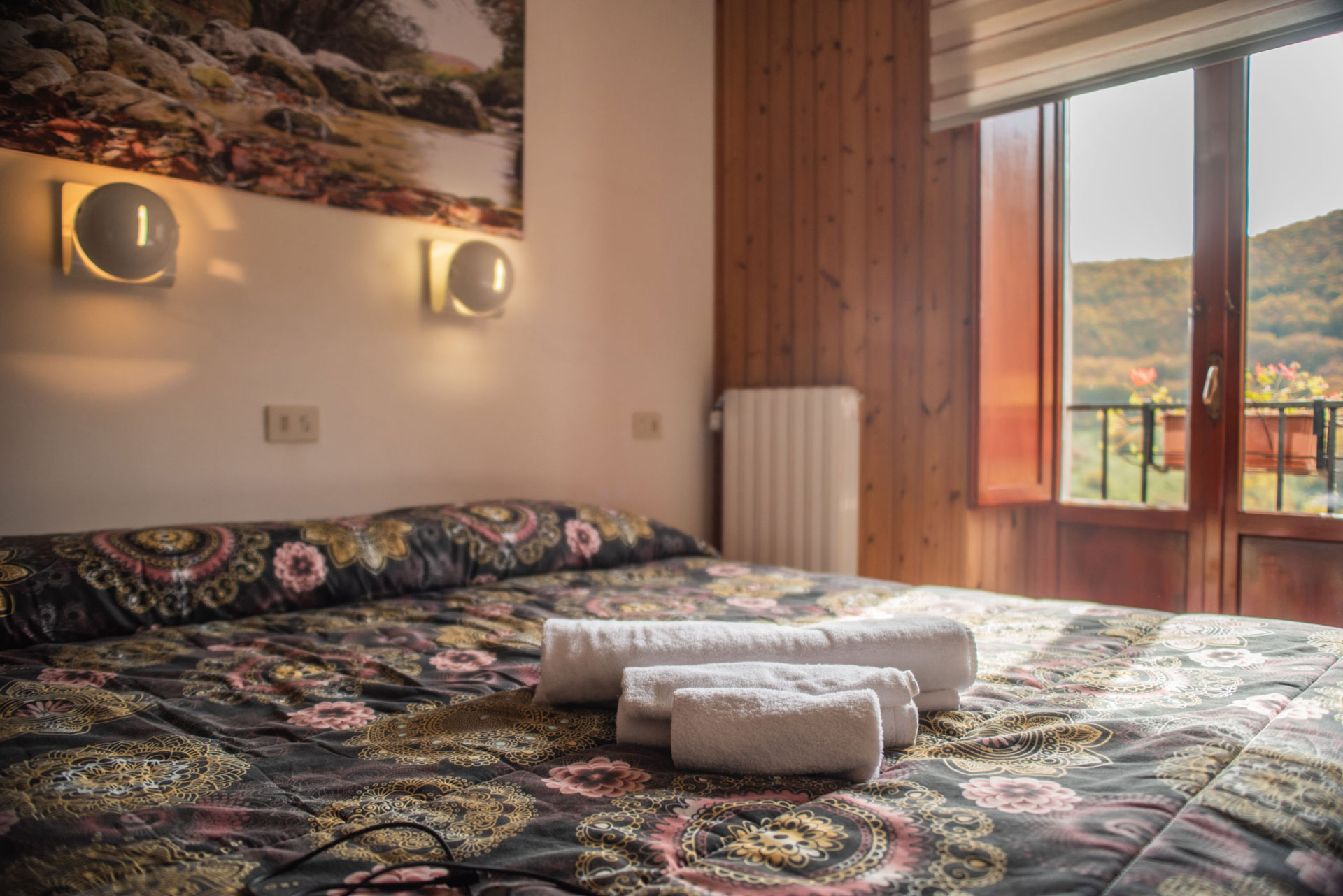 Dettagli Camere – Particolari delle camere con arredi in legno, atmosfera calda e vista sulle montagne.